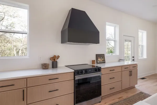 a kitchen with kitchen island a stove a sink dishwasher a refrigerator and white cabinets with wooden floor
