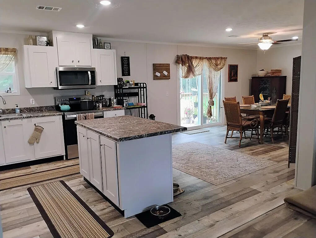 650 Satellite Road Graceville, FL 32440 - Photo 10 of 23 a kitchen with stainless steel appliances granite countertop a stove top oven a sink dishwasher a dining table and chairs with wooden floor