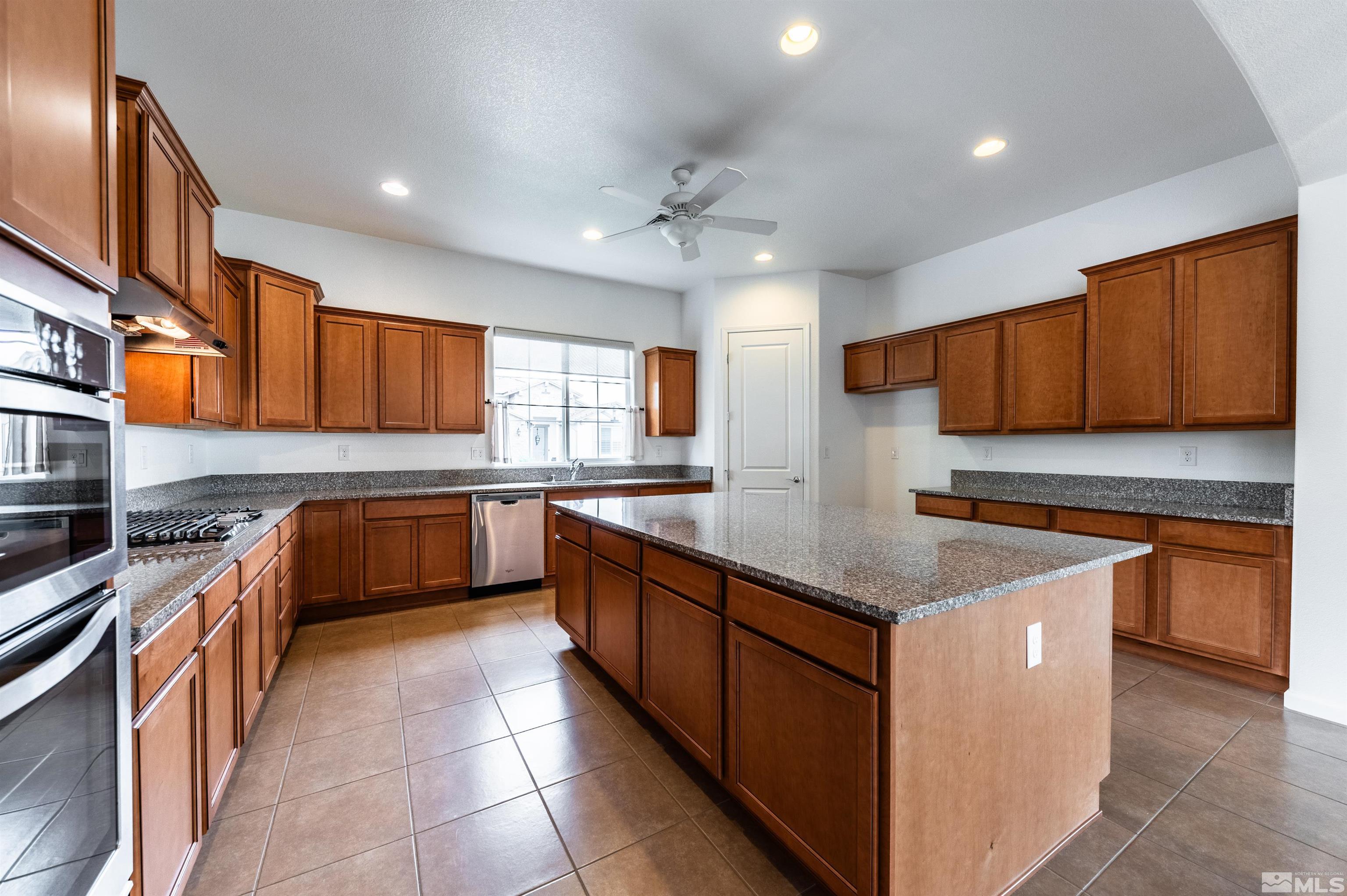 2305 Trakehner Lane Reno, NV 89521 - Photo 14 of 40 a kitchen with stainless steel appliances granite countertop a sink counter space cabinets and a large window