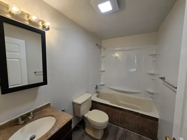 a bathroom with a granite countertop sink toilet and shower