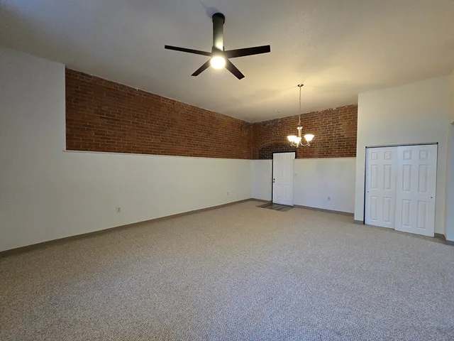 an empty room with ceiling fan and window