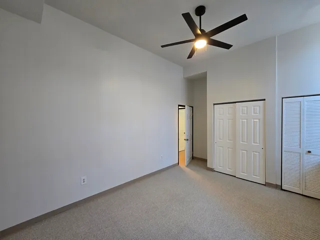an empty room with closet and a ceiling fan