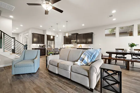 a living room with furniture kitchen view and a chandelier