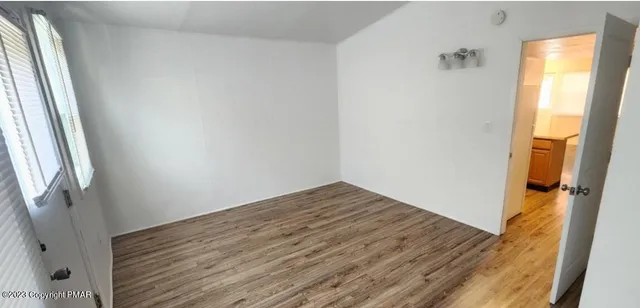 a view of empty room with wooden floor and window