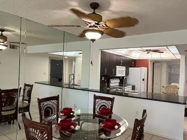a dinning room with kitchen island stainless steel appliances furniture and a chandelier