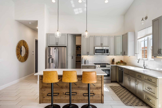 4222 Hampshire Road Hurricane, UT 84737 - Photo 4 of 12 Modern kitchen featuring a wood-finish island with a white countertop, stainless steel appliances, light gray cabinetry, subway tile backsplash, and recessed lighting