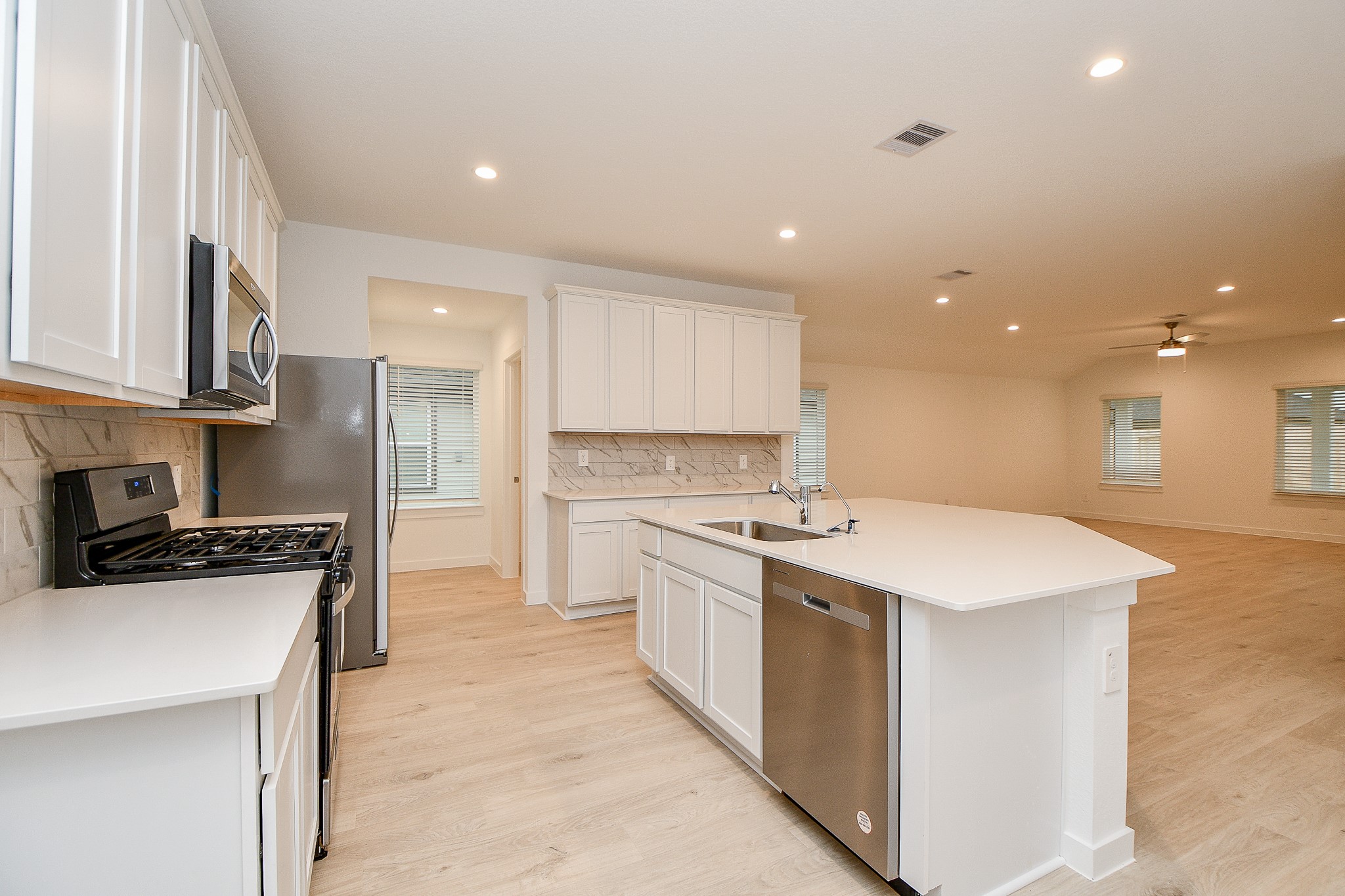 31715 Hallington Hl Lane Fulshear, TX 77441 - Photo 3 of 37 a kitchen with a stove a sink a refrigerator and a microwave