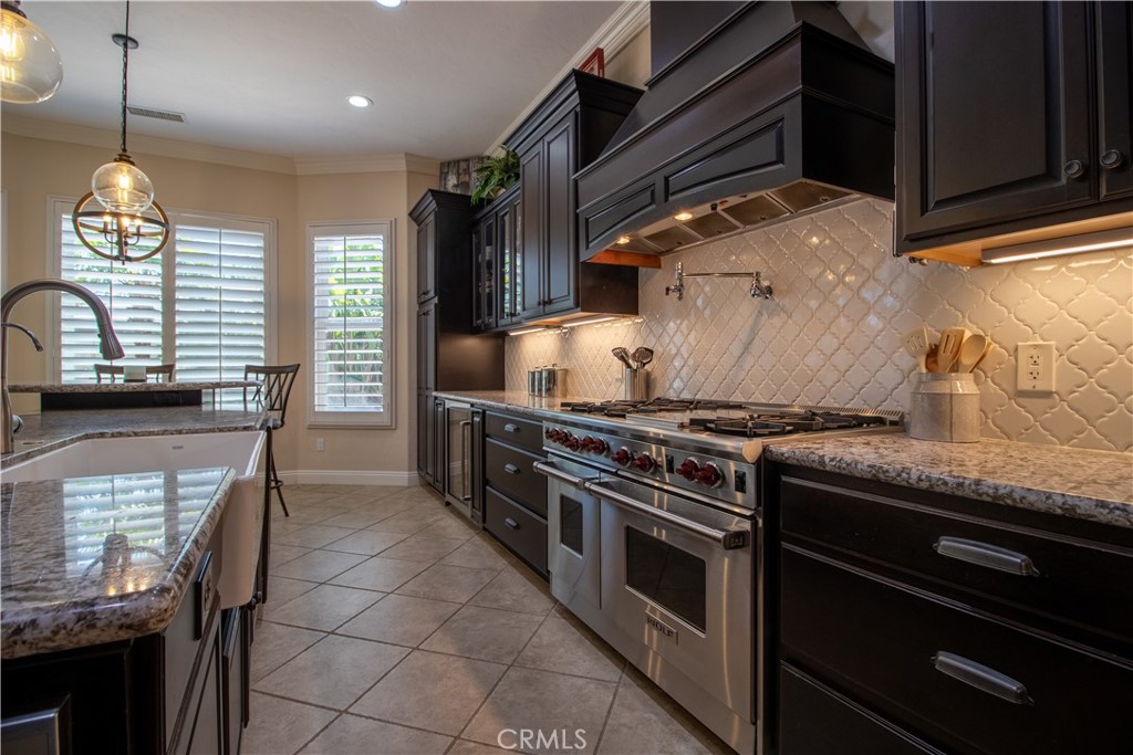 33699 Spring Brook Circle Temecula, CA 92592 - Photo 17 of 83 a kitchen with granite countertop a stove and a wooden cabinets