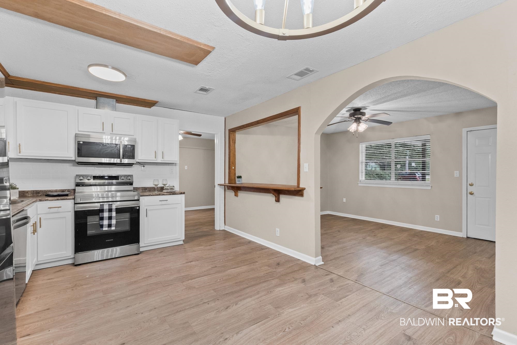 1560 Military Road Mount Vernon, AL 36560 - Photo 5 of 26 Kitchen featuring white cabinetry, stainless steel appliances, and wood-finish flooring