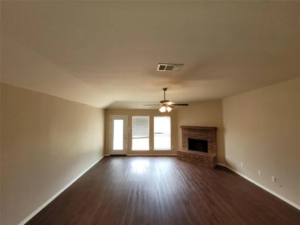 an empty room with wooden floor fireplace and windows