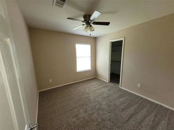 an empty room with a ceiling fan and window