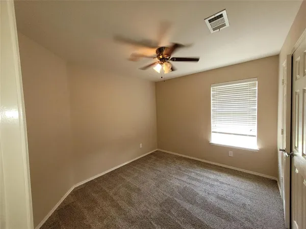 a view of empty room with a ceiling fan and a window