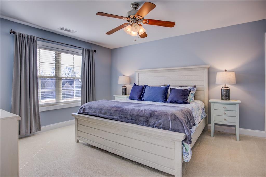 1021 Arbor Court Madison, GA 30650 - Photo 41 of 64 a spacious bedroom with a bed and a chandelier