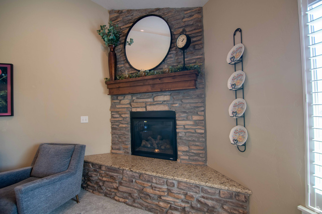 646 East 1400th Street North Mapleton, UT 84664 - Photo 15 of 78 Corner fireplace featuring a stone surround, a wood mantel, a clear glass door, and a granite hearth