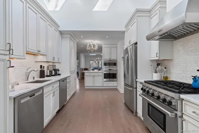 a kitchen with stainless steel appliances a stove a sink and white cabinets