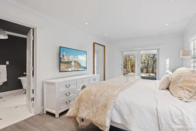 a bedroom with a bed and a flat tv screen on dresser