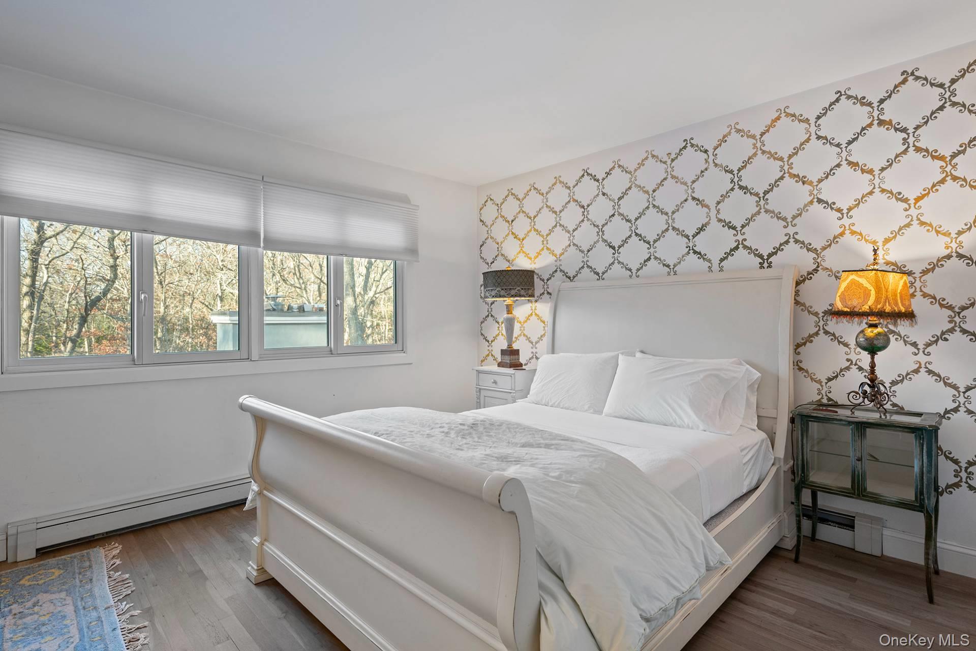 1824 Majors Path Southampton, NY 11968 - Photo 26 of 28 Bedroom with baseboard heating, wood finished floors, wallpapered walls, and an accent wall