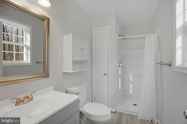 a bathroom with a toilet sink vanity and mirror