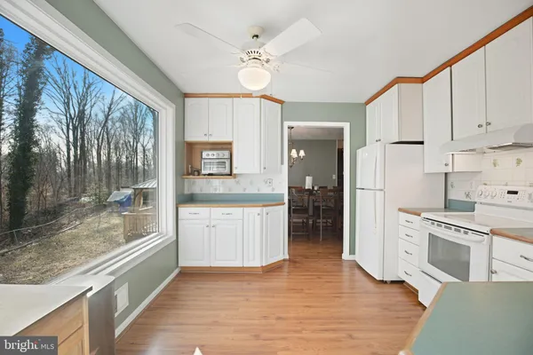 a large white kitchen with granite countertop a stove top oven a sink a counter space and cabinets