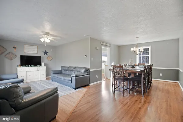 a living room with furniture a wooden floor and a view of kitchen