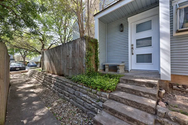 a view of a house with a small yard and large tree and wooden fence