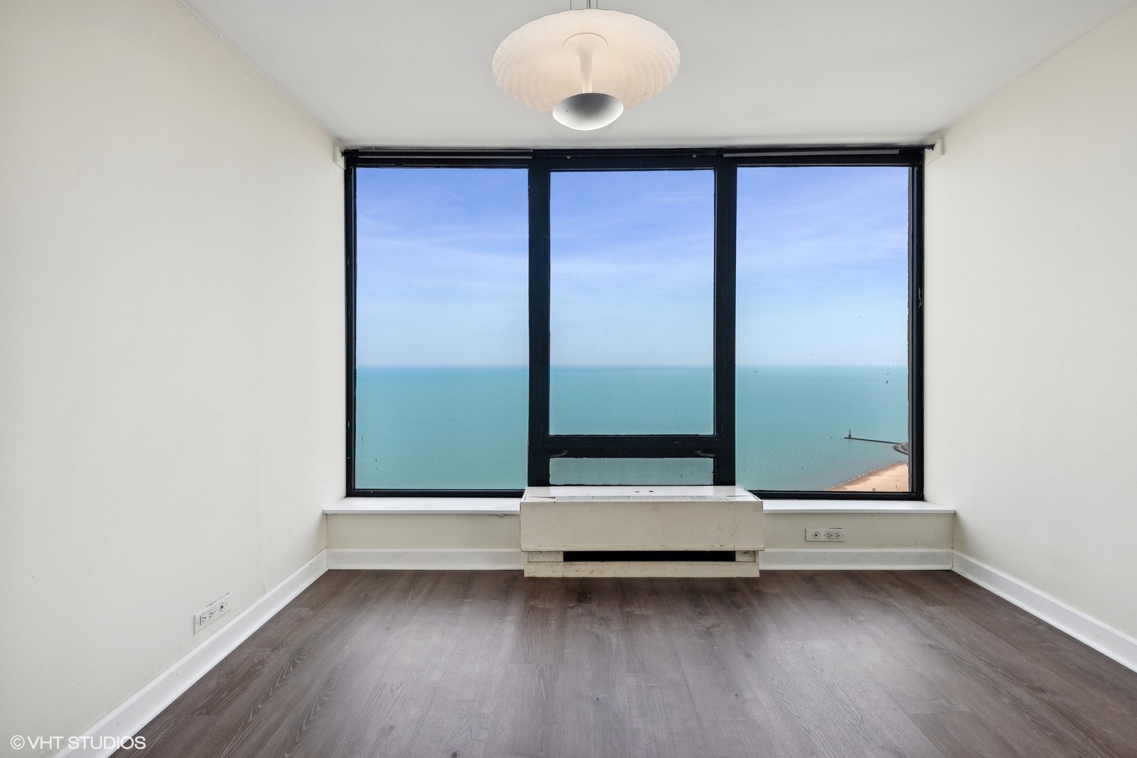 5445 North Sheridan Road, Unit 3812 Chicago, IL 60640 - Photo 7 of 21 an empty room with wooden floor and windows