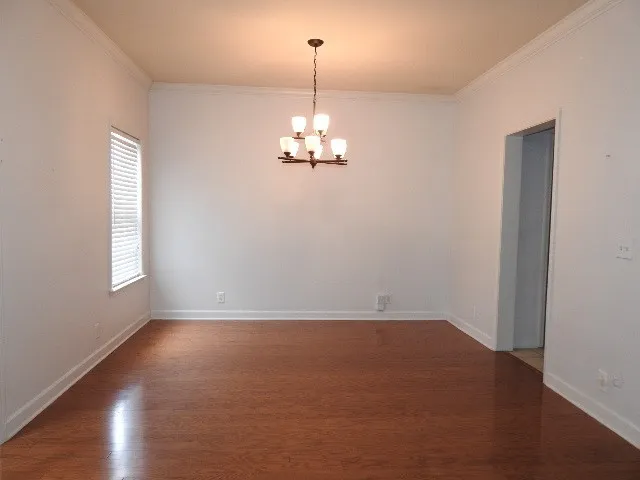 an empty room with wooden floor windows and chandelier