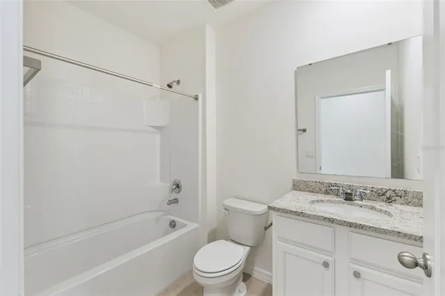a bathroom with a granite countertop sink a toilet and shower