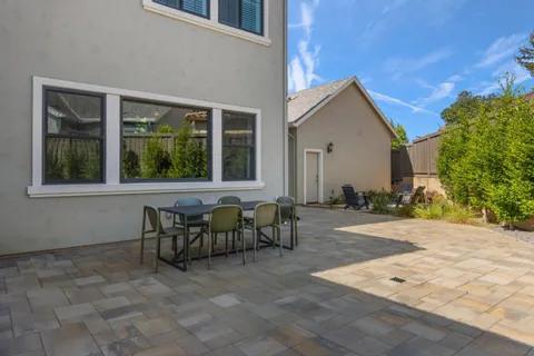 a view of a patio with table and chairs with plants and wooden fence