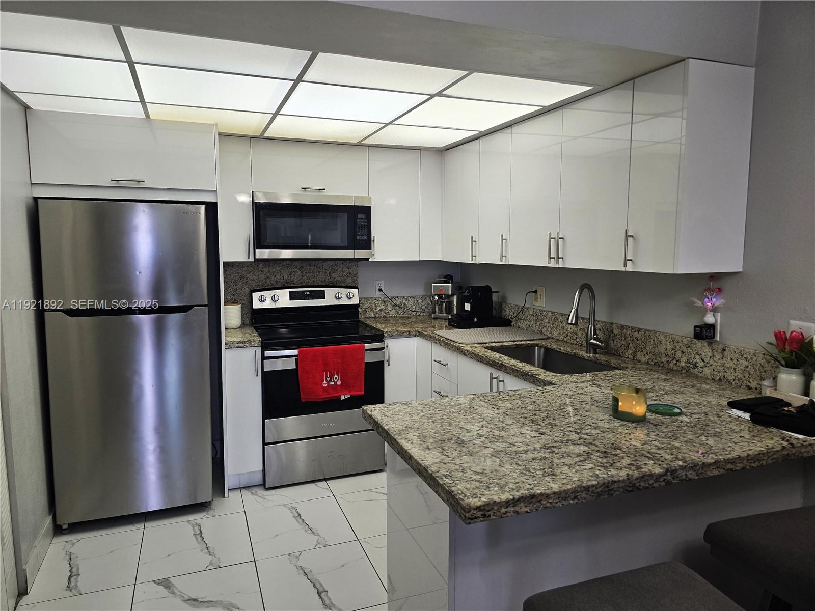 1750 West 56th Street, Unit 216 Hialeah, FL 33012 - Photo 12 of 14 a kitchen with a refrigerator a stove and a sink