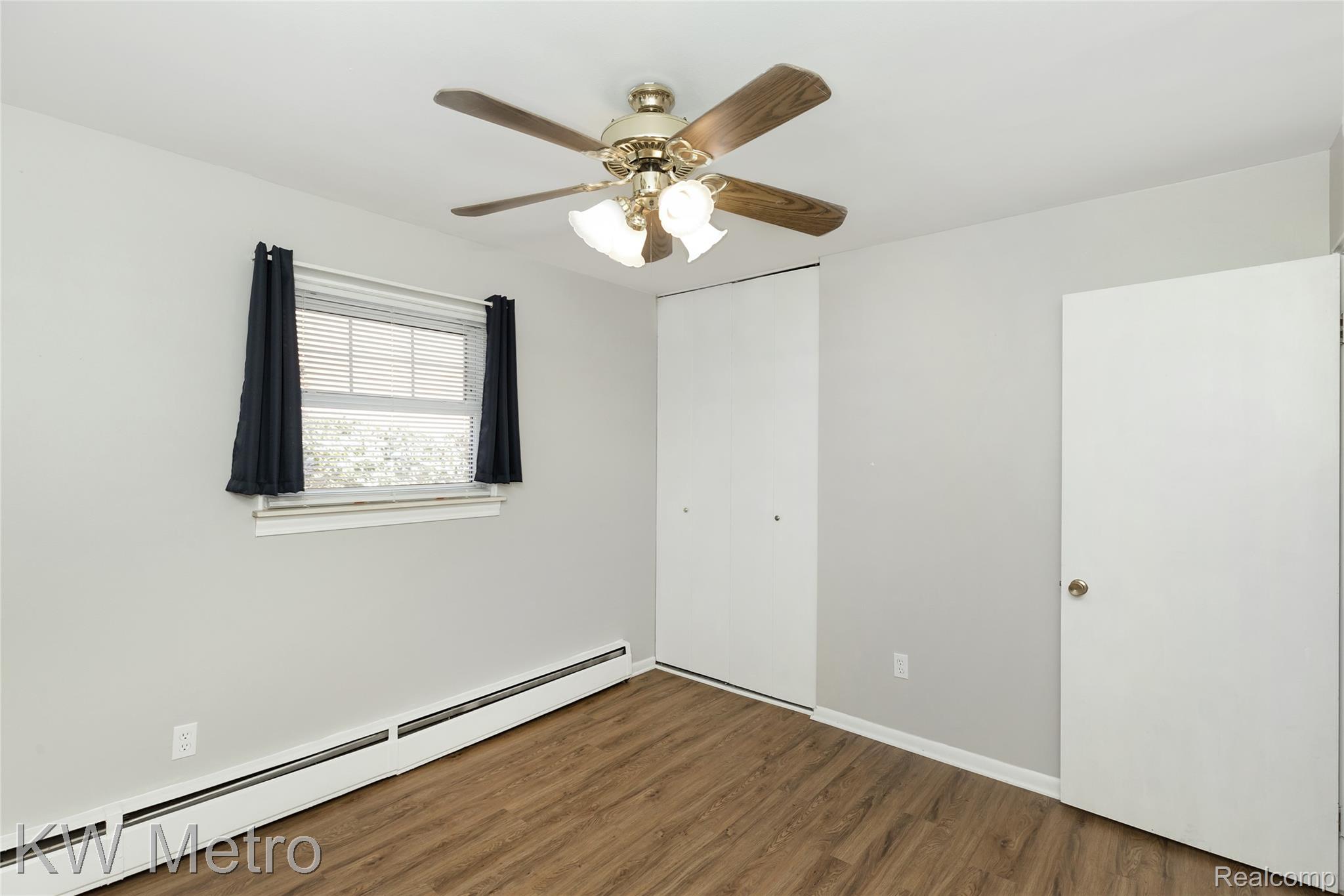 2817 West 13 Mile Road Royal Oak, MI 48073 - Photo 13 of 21 Unfurnished bedroom with a baseboard radiator, a ceiling fan, wood finished floors, and a closet
