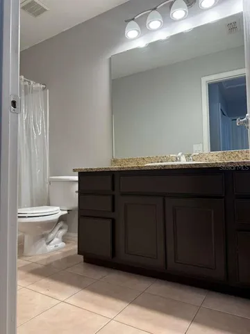 a bathroom with a granite countertop sink and a toilet