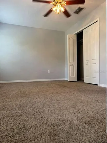 an empty room with a ceiling fan and window