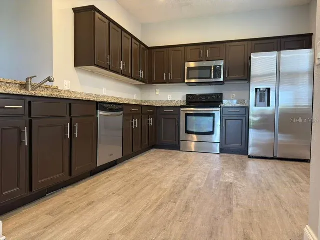 a kitchen with stainless steel appliances granite countertop a stove a sink and a microwave