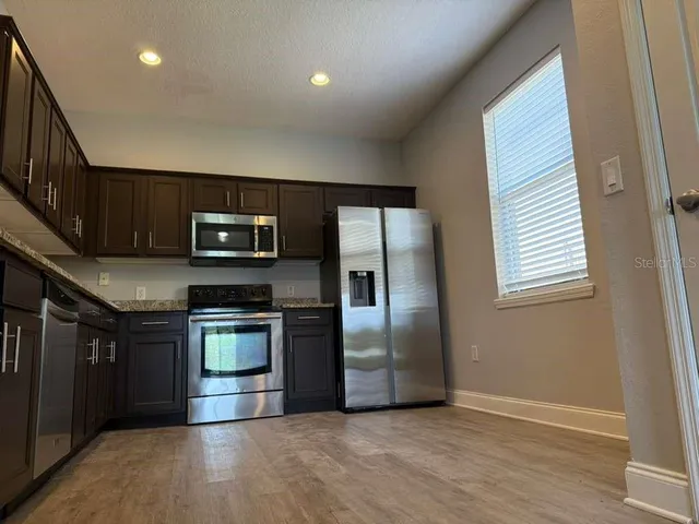 a kitchen with stainless steel appliances granite countertop a refrigerator a stove a sink and a microwave