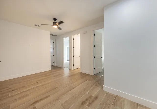 an empty room with wooden floor ceiling fan and window