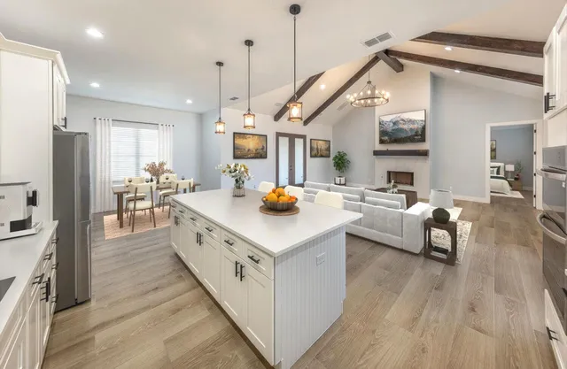 a kitchen with stainless steel appliances a stove a sink dishwasher a refrigerator white cabinets with wooden floor