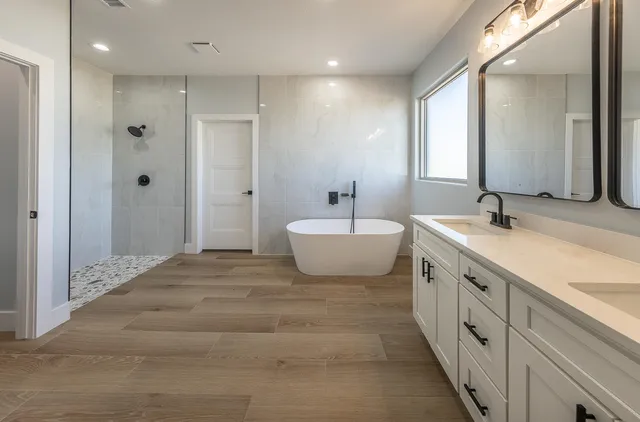 a spacious bathroom with a double vanity sink a mirror and a bathtub