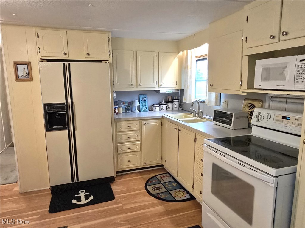 Kitchen featuring appliances, sink, and light laminate flooring