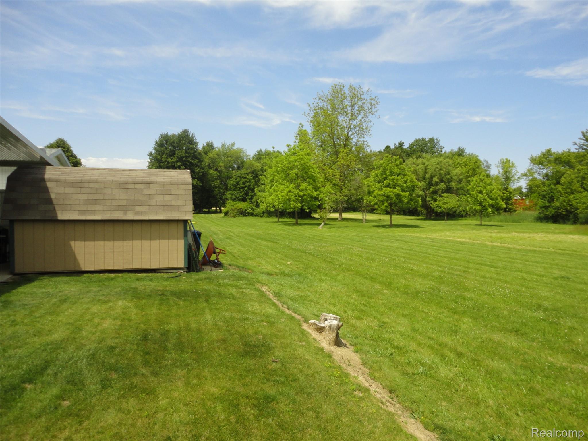 463 Edinborough Temperance, MI 48182 - Photo 21 of 23 Expansive green lawn with mature trees and a detached shed featuring a shingle roof and tan siding