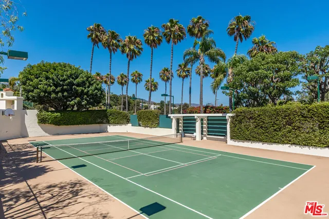 a view of a tennis ground with a large trees in the background