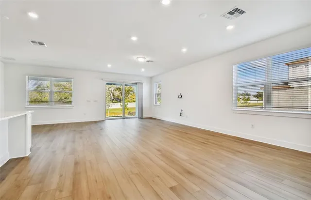 an empty room with wooden floor and windows