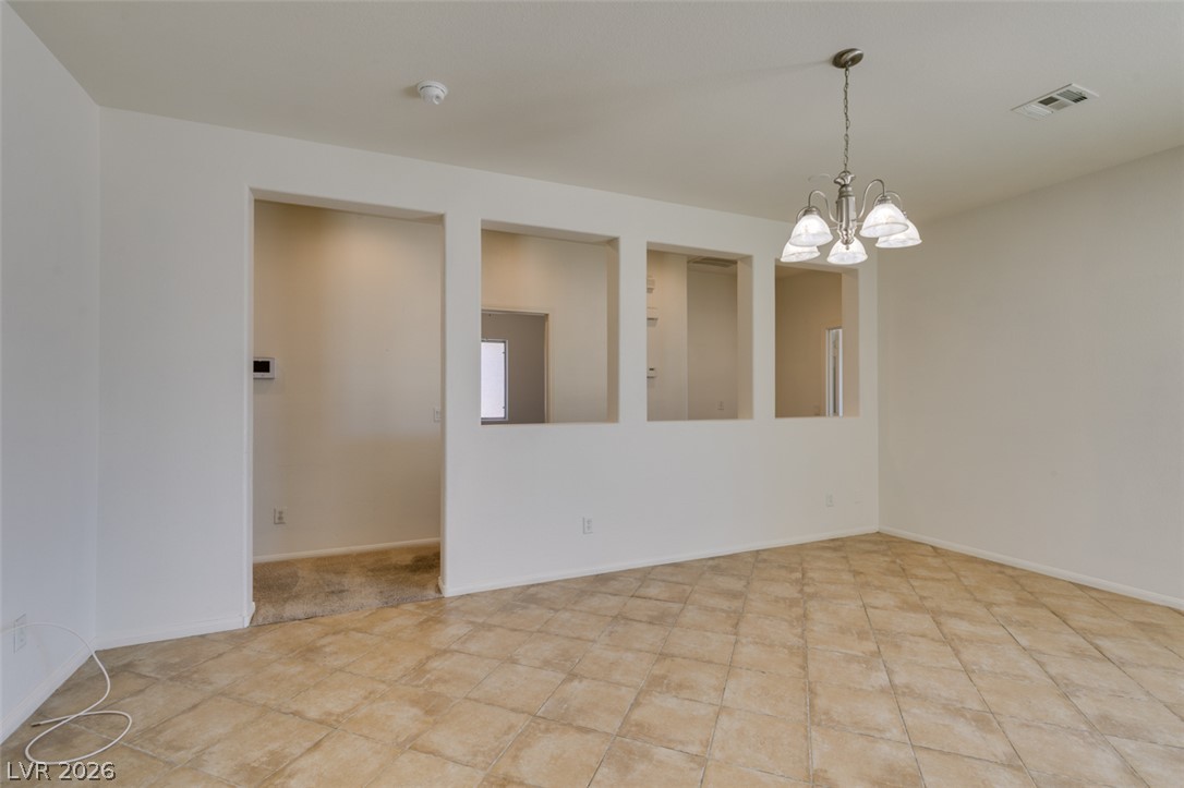 5150 Riverside Run Court North Las Vegas, NV 89081 - Photo 18 of 50 A versatile open-plan area features tile flooring and a classic chandelier, offering a seamless flow for living and dining.