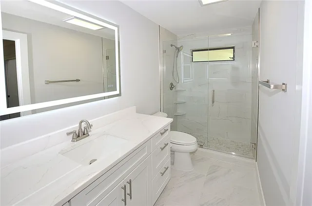 a bathroom with a sink a toilet and shower