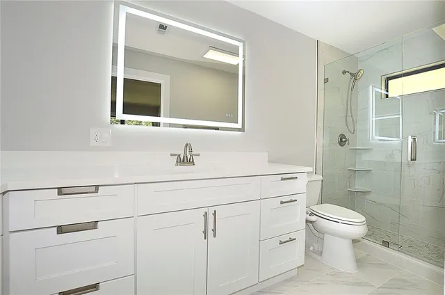a bathroom with a toilet sink vanity and mirror