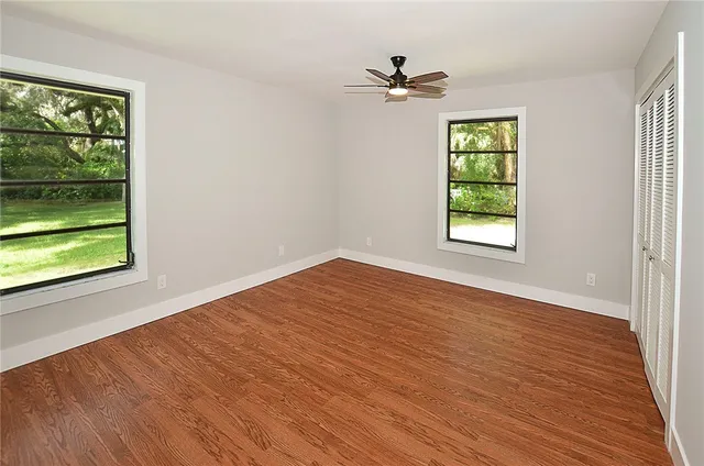 a view of an empty room with a window and wooden floor