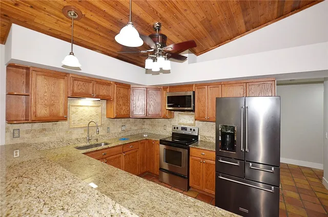 a kitchen with stainless steel appliances granite countertop a refrigerator a stove and a sink