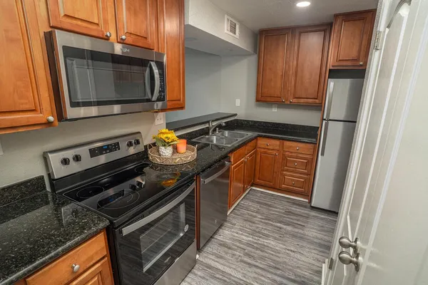 a kitchen with granite countertop a stove microwave and sink