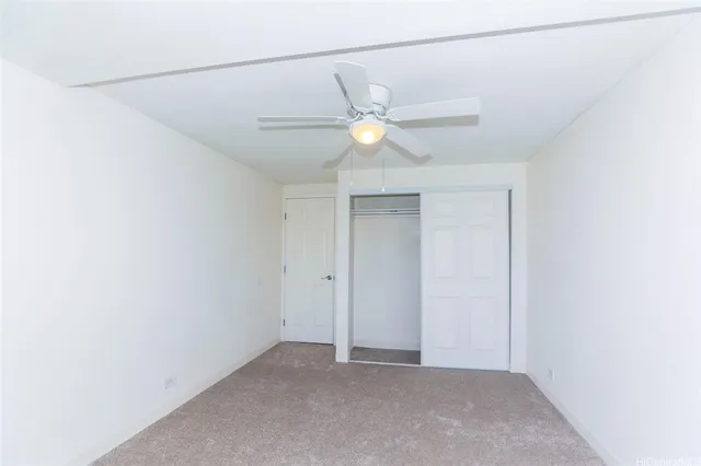 an empty room with closet and a ceiling fan