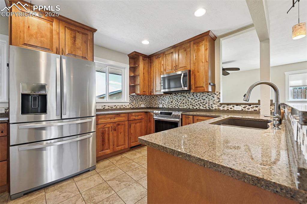 1305 Sunset Road Colorado Springs, CO 80909 - Photo 11 of 50 a kitchen with stainless steel appliances granite countertop a refrigerator a stove a sink and a microwave